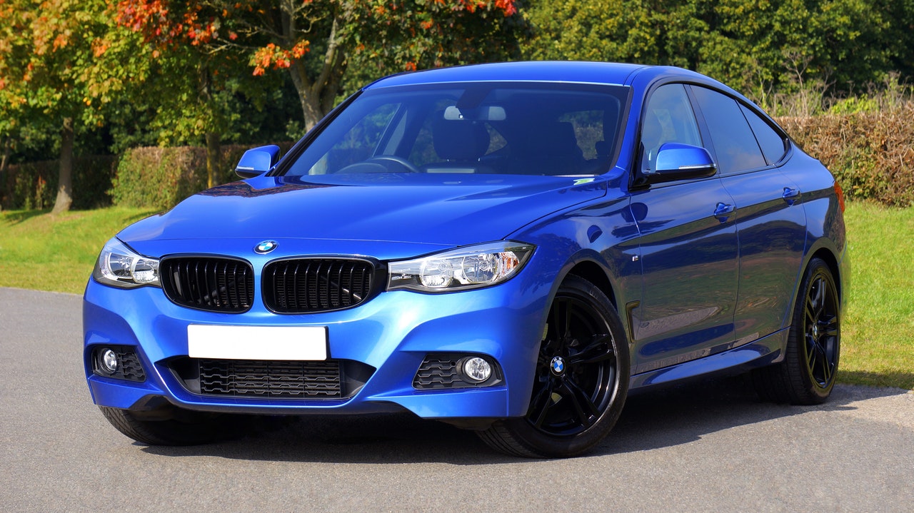 Blue Sedan on Gray Pavement, Near Some Grass