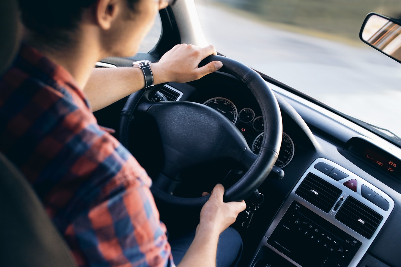 Male Driver Holding onto Steering Wheel of Car 